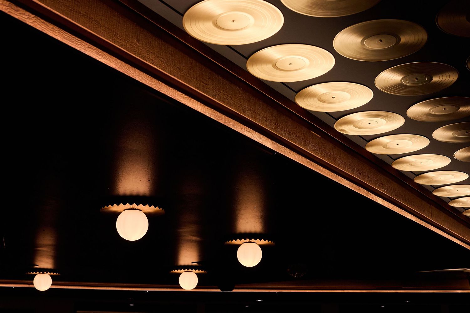 Decorative circular ceiling lights creating an ambient glow against a dark ceiling in an indoor venue.