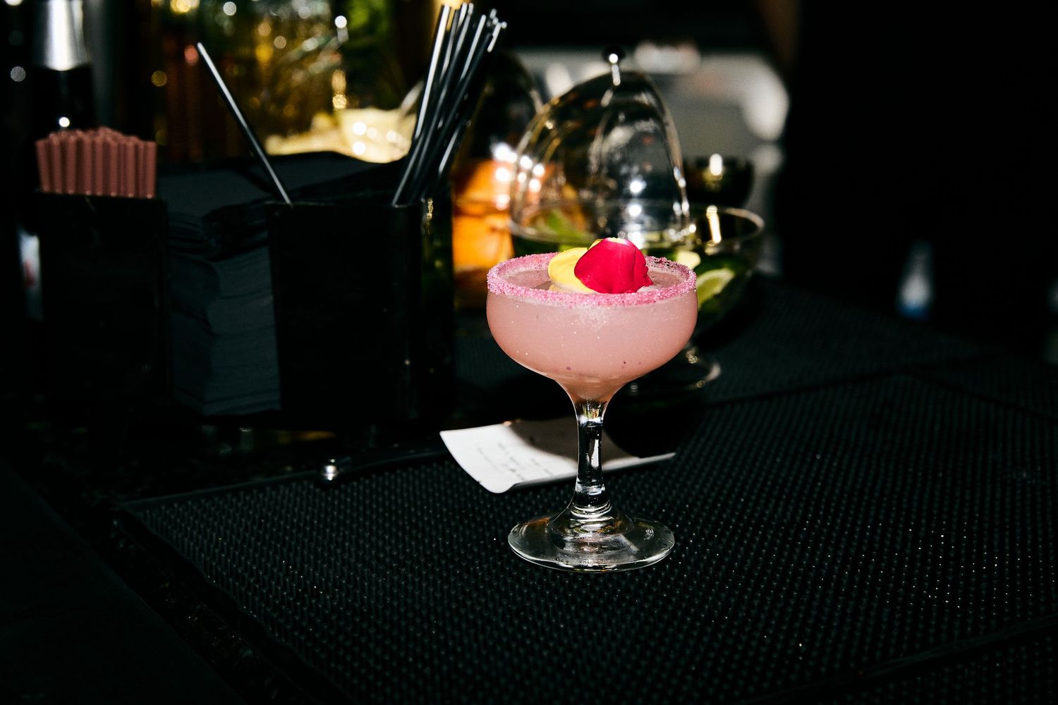 Dark cocktail lounge setting with glassware silhouettes on a bar counter.