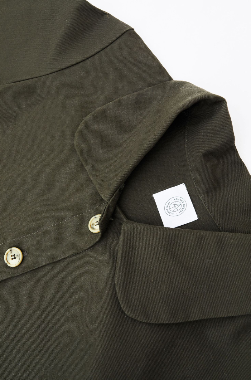 Close-up of an olive green jacket collar with button detail and brand tag.