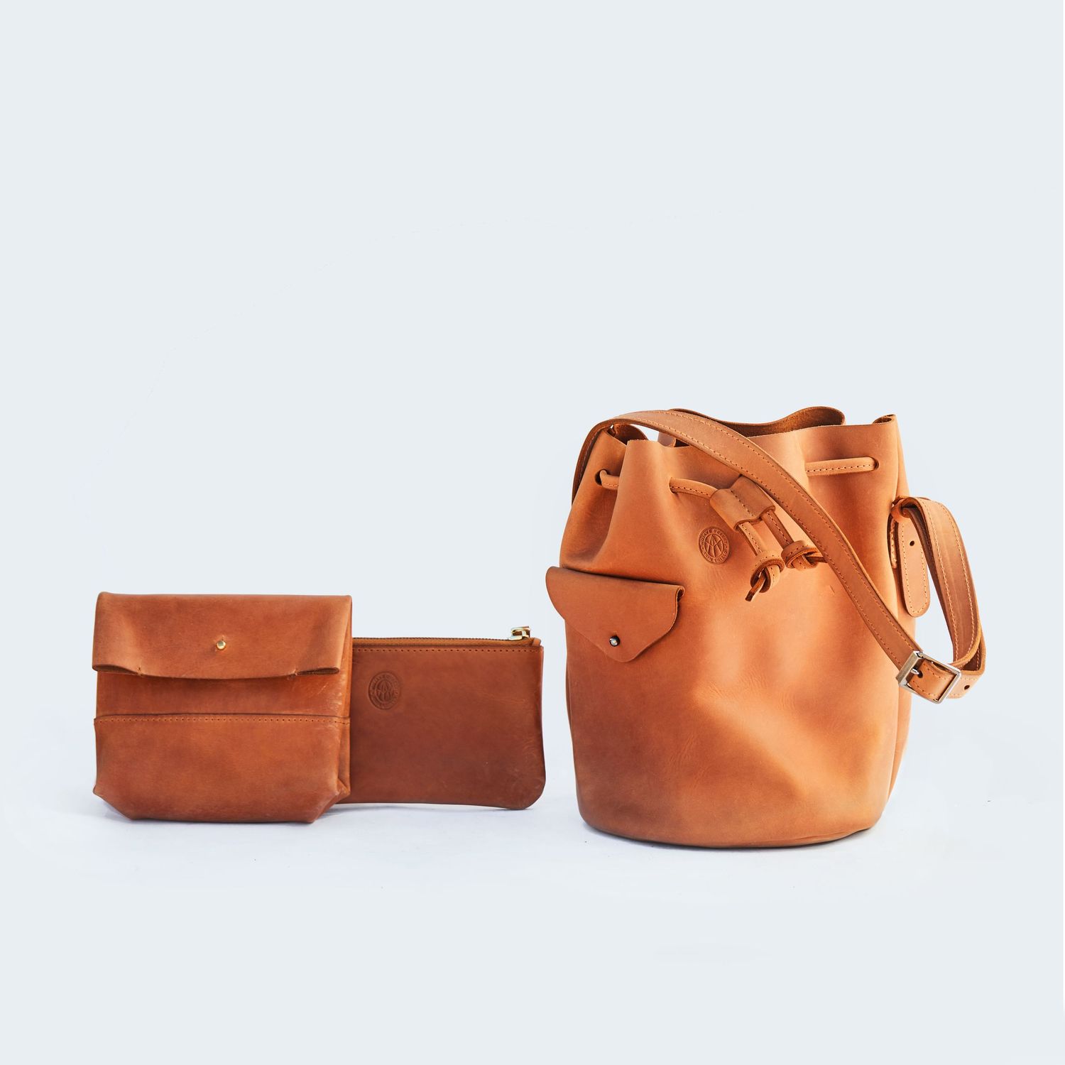 Cognac brown leather bucket bag and matching small pouch photographed on white background.