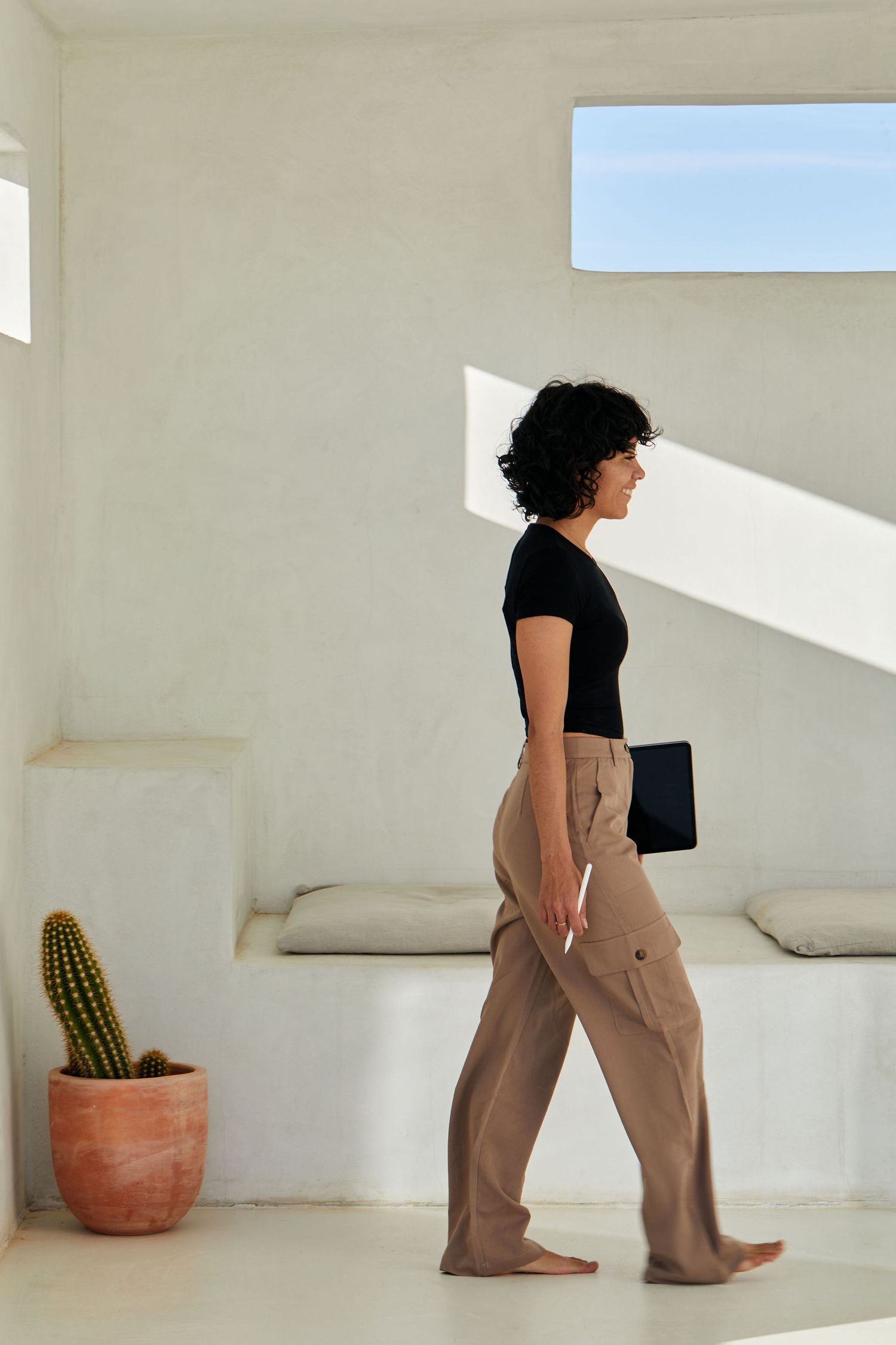 Minimalist white room interior with window light and potted cactus.
