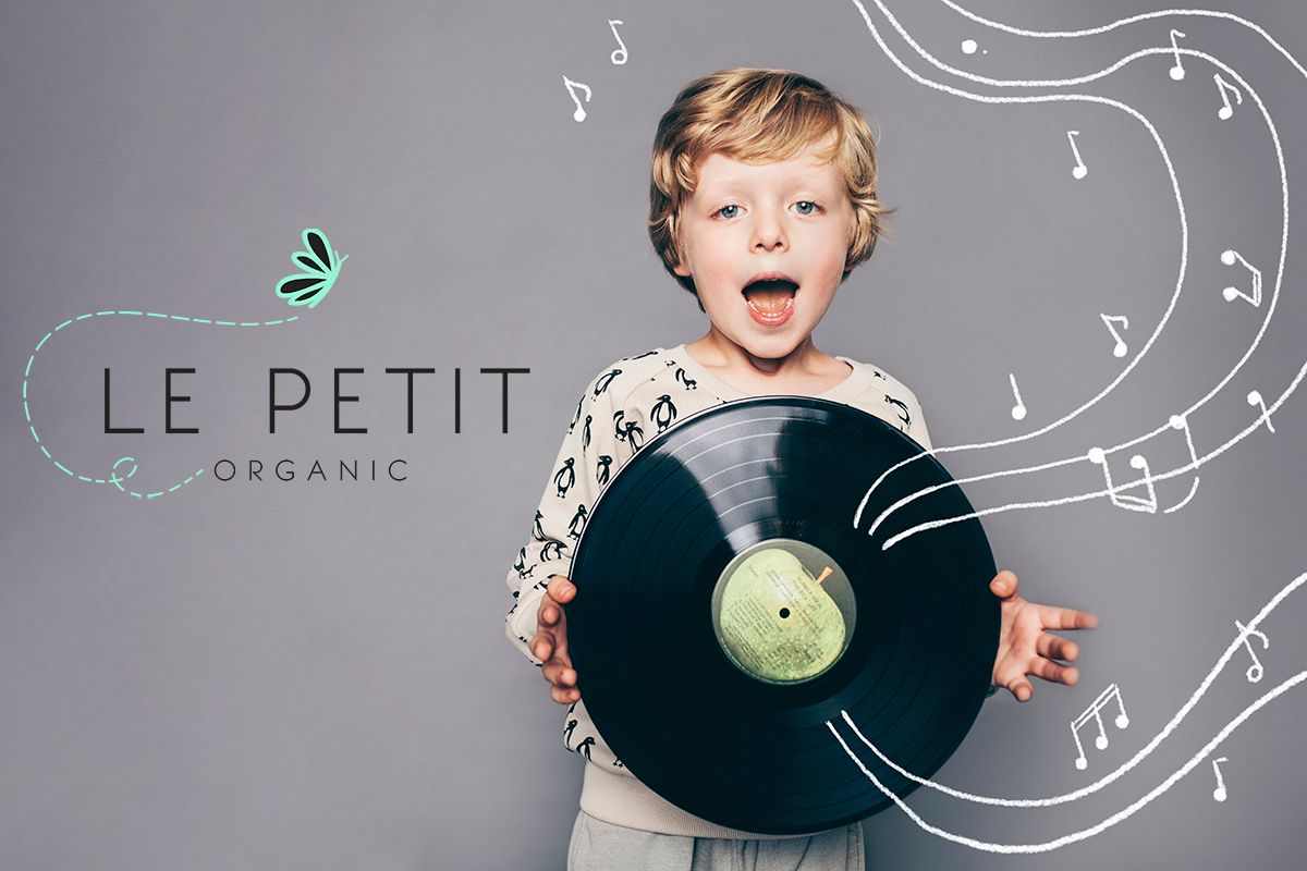 A young child holds a vinyl record against a gray background with musical notes and Le Petit Organic branding artwork.