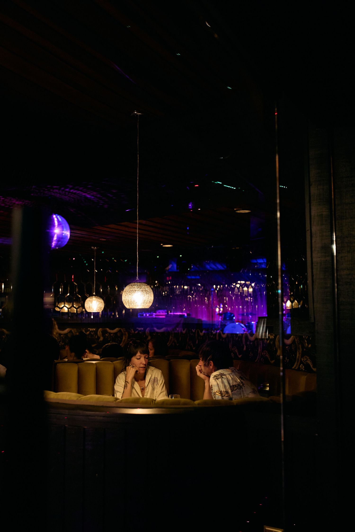 Dark restaurant interior with glowing spherical pendant lights and purple ambient lighting in the background.