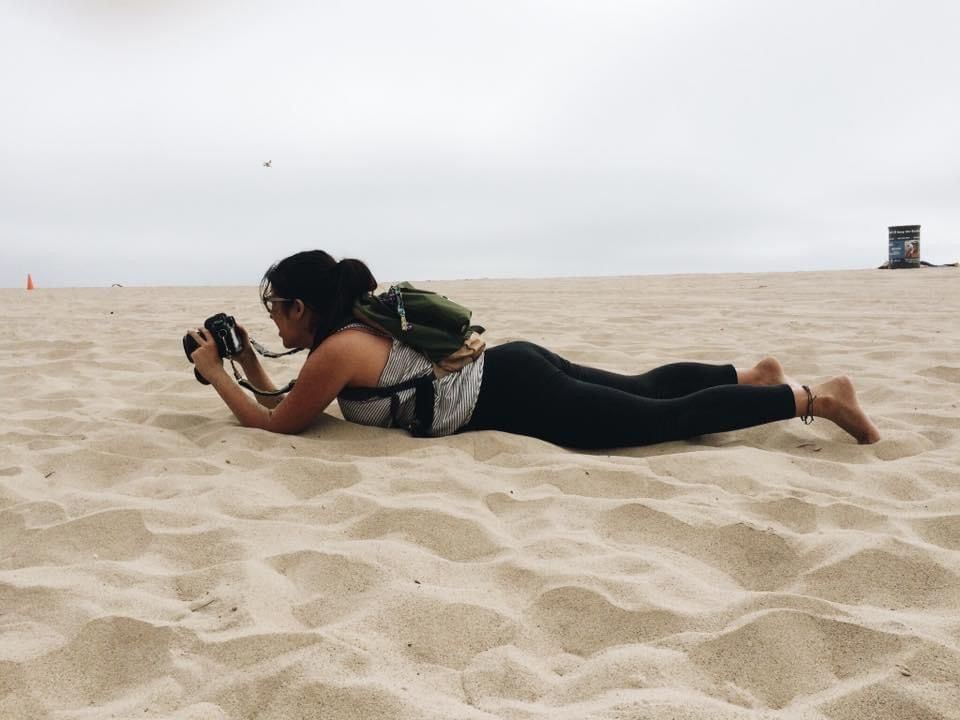A figure lying face down on the sandy beach reaches forward against strong winds in a series of sequential photos.