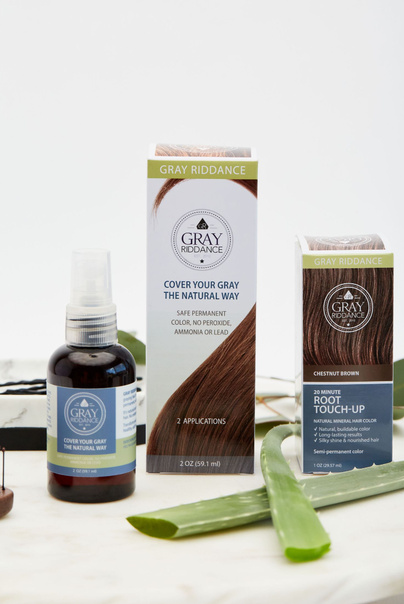 Natural gray hair coverage products with aloe vera leaves and dropper bottle on white surface.