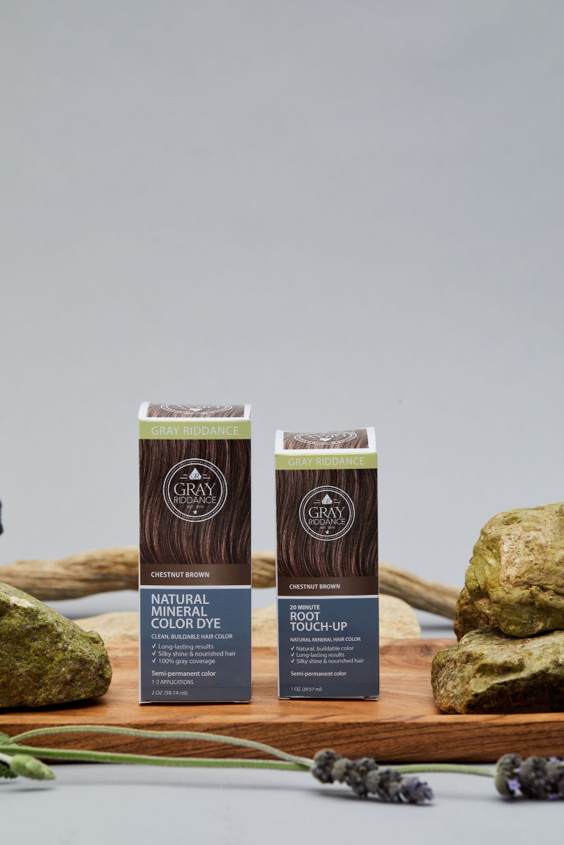 Two Gray Radiance hair care product boxes displayed with natural elements on wooden surface.