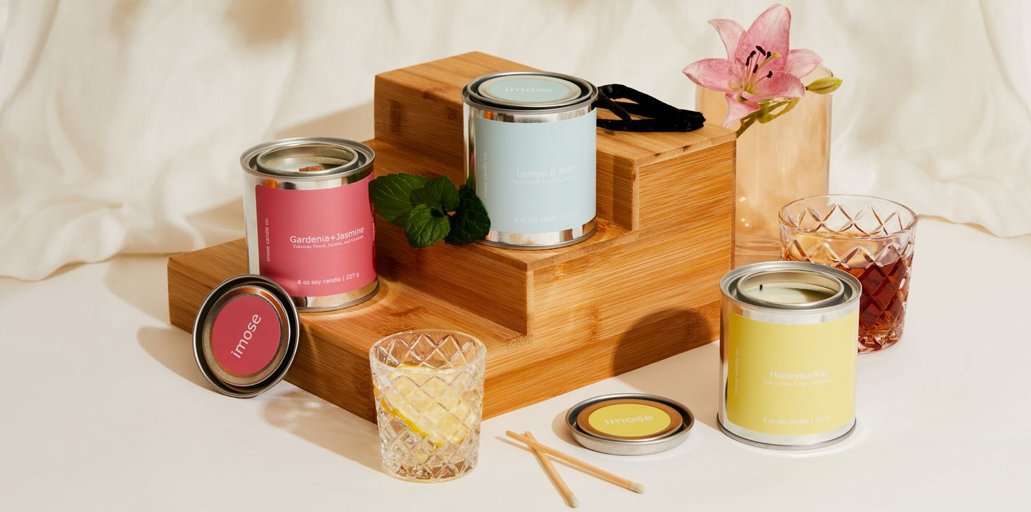 Wooden display stand with colorful candle tins and crystal glassware in soft lighting.