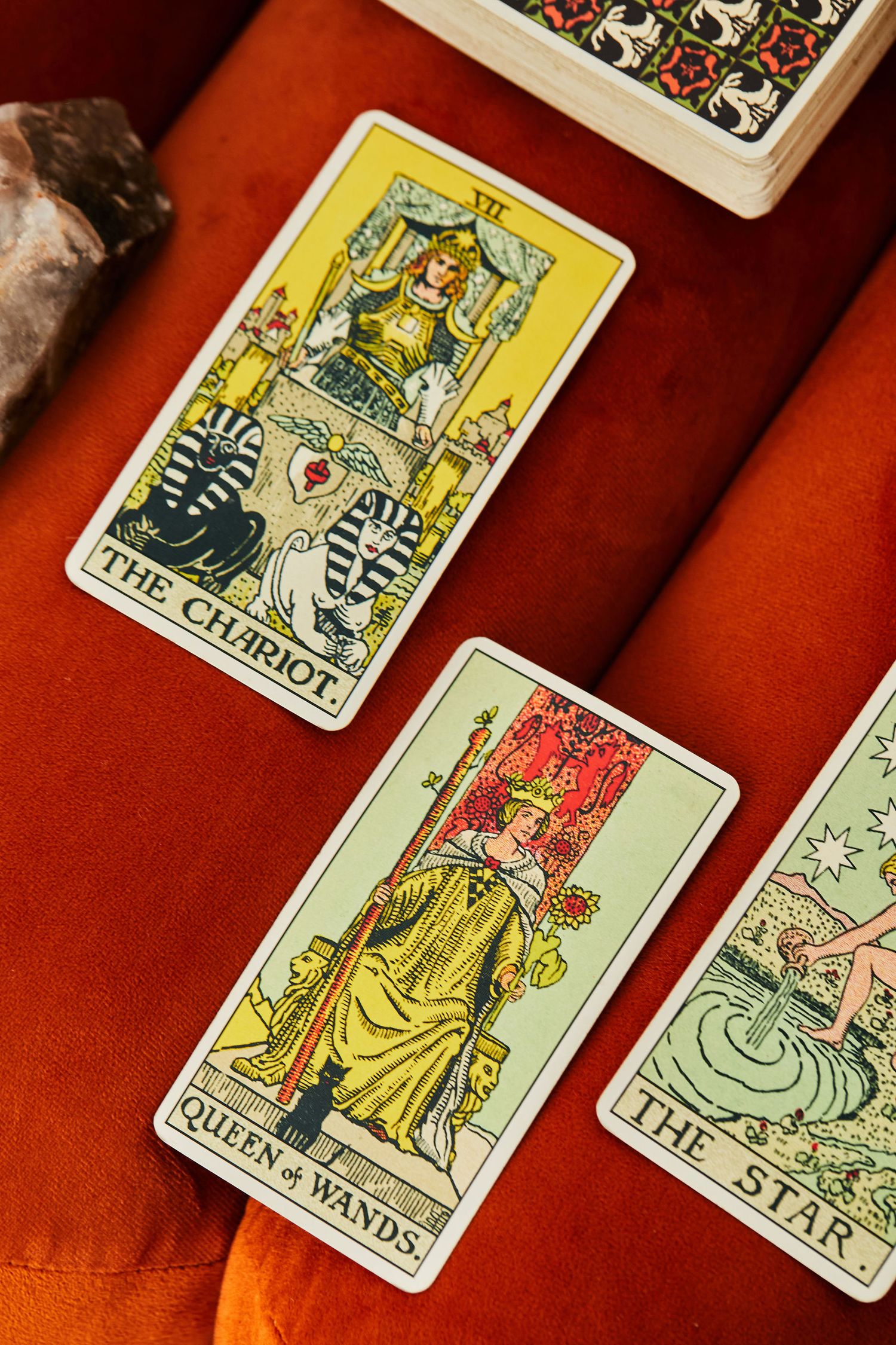 Three tarot cards displayed on red velvet: The Chariot, Queen of Wands, and The Star from Rider-Waite deck.