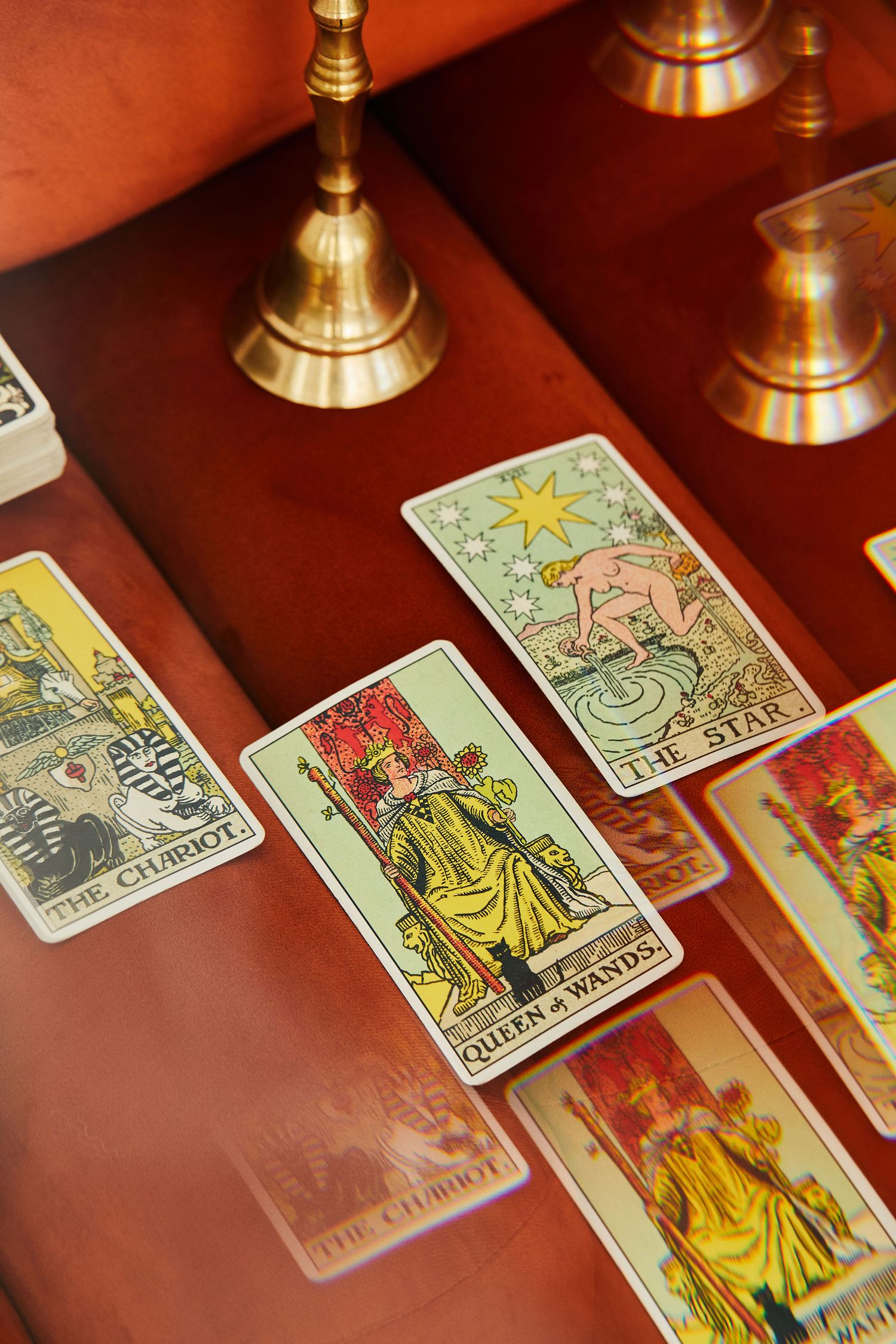 Tarot cards including Queen of Wands and The Star spread on a wooden table with brass candlesticks.