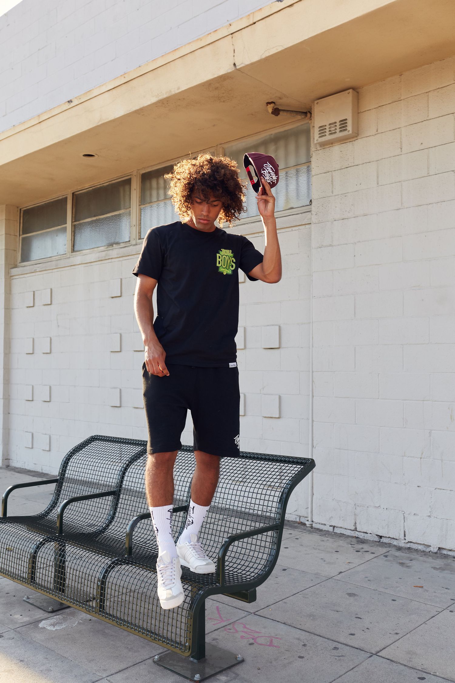 Athletic urban style photo of person posing on metal bench in streetwear.