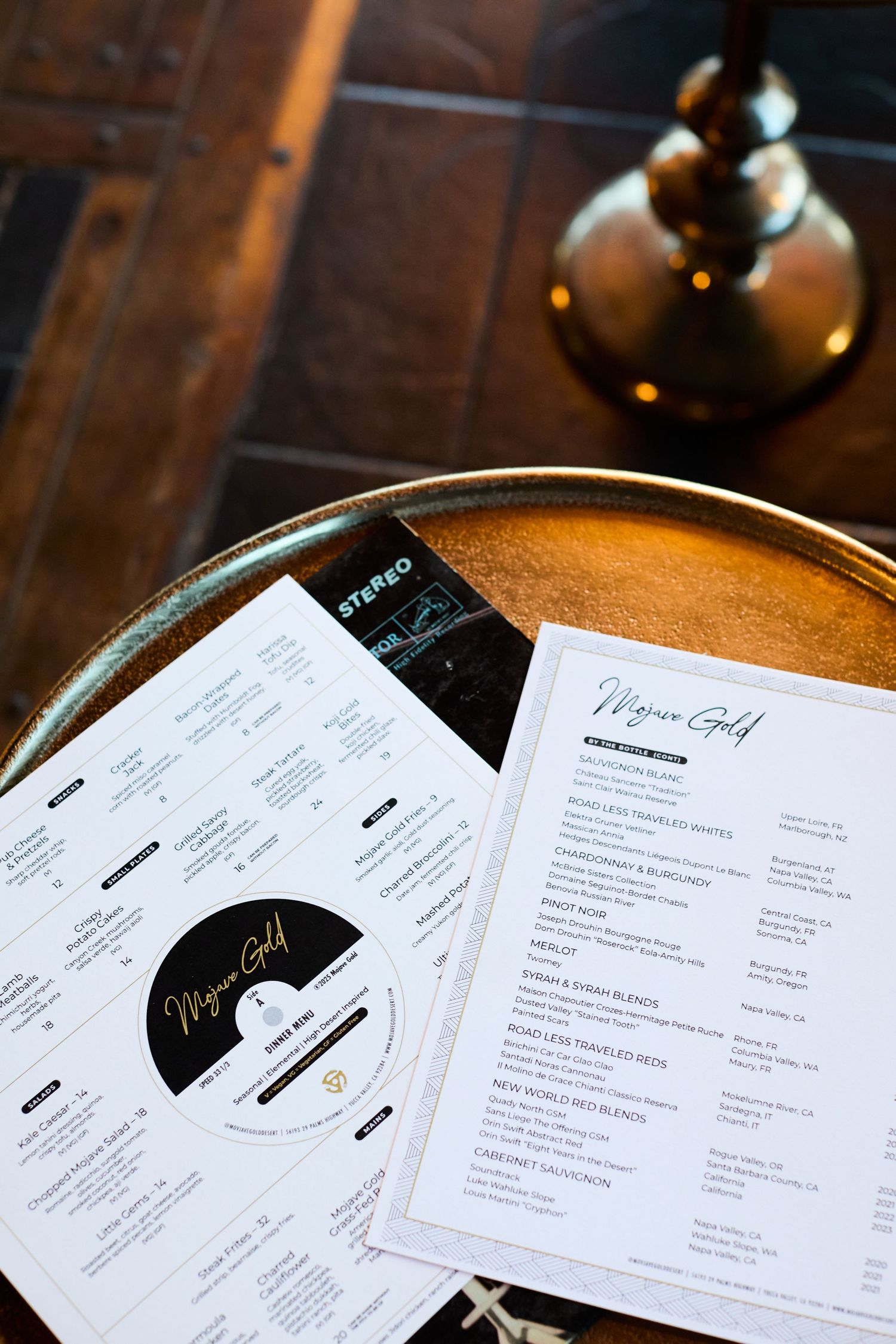 Restaurant menu cards displayed on wooden surface with hanging pendant light fixture in background.