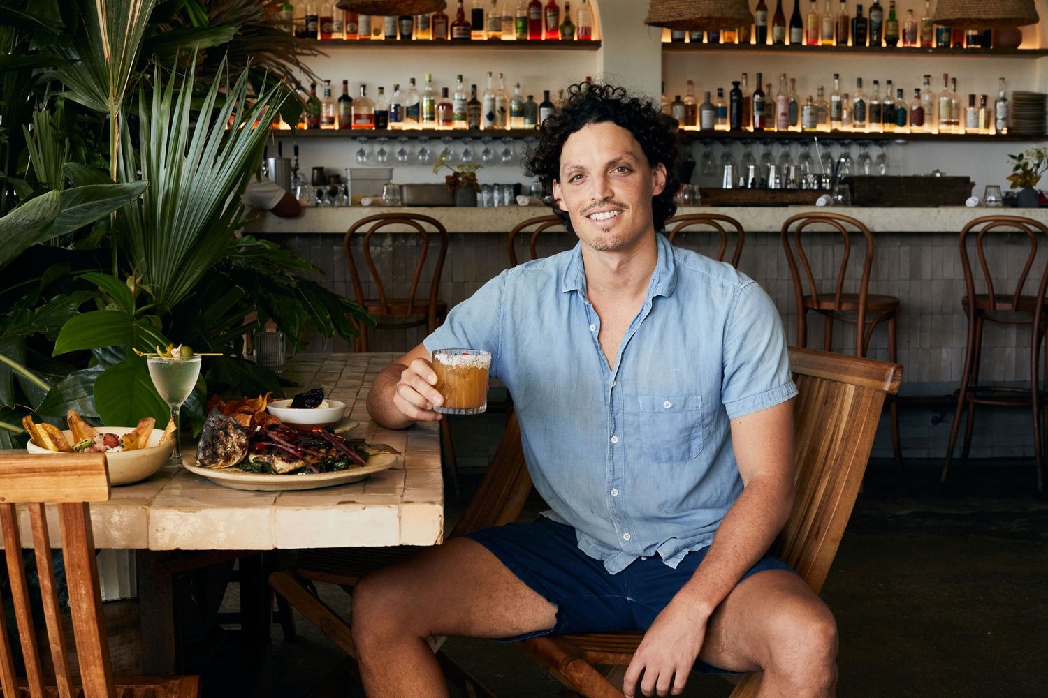 Tropical-themed restaurant bar interior with wood accents and lush plants.