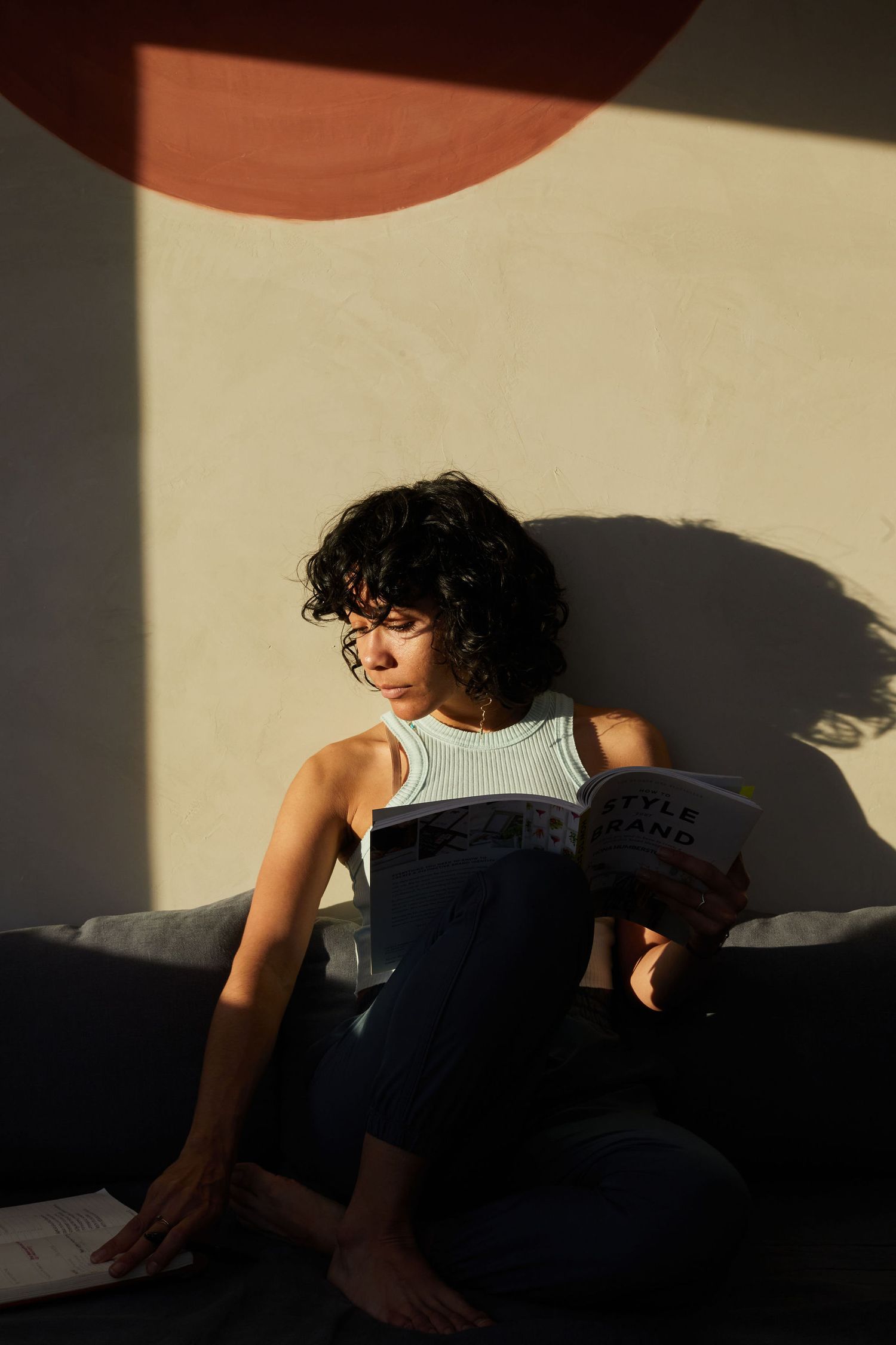 Artistic portrait in dramatic lighting showing person sitting on dark couch.