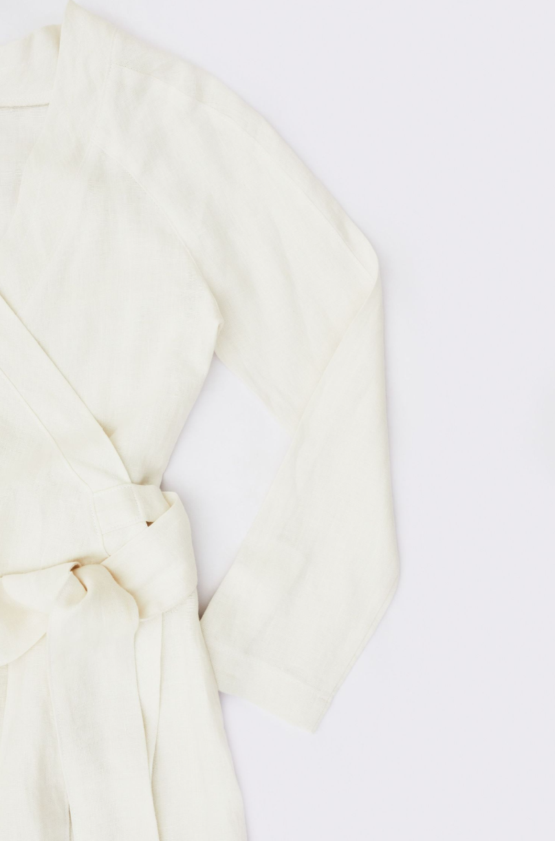 Cream colored wrapped dress sleeve detail against white background.