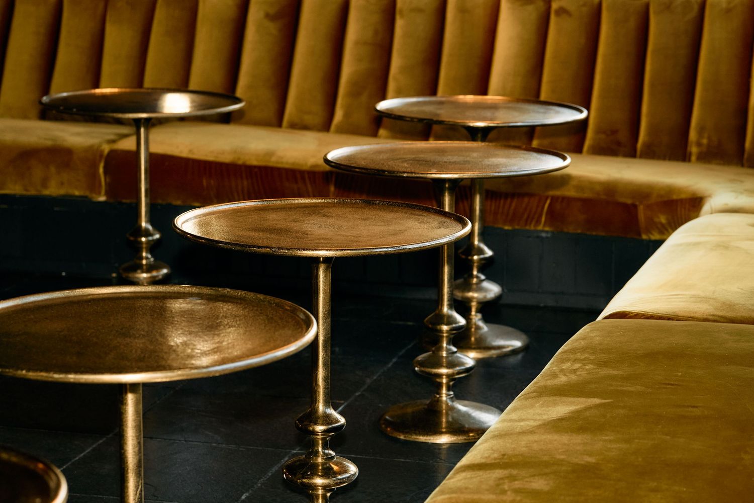 Vintage cymbals from drum kit positioned in a row with warm lighting casting golden reflections on their surfaces.