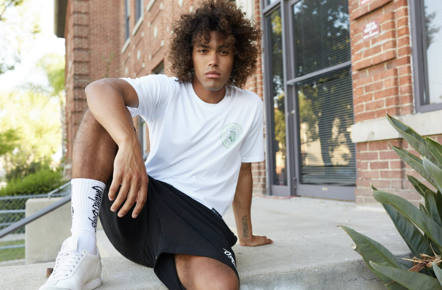 Person in black shorts and white t-shirt posing against Jungle Boys wall art.
