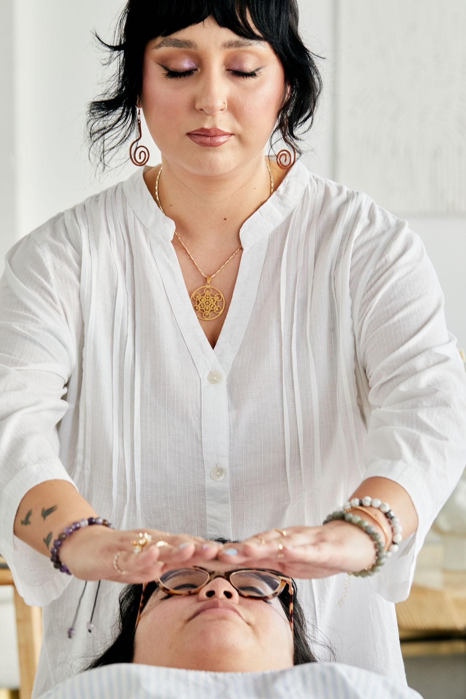 Reiki healer in white linen shirt performing energy healing session on client.