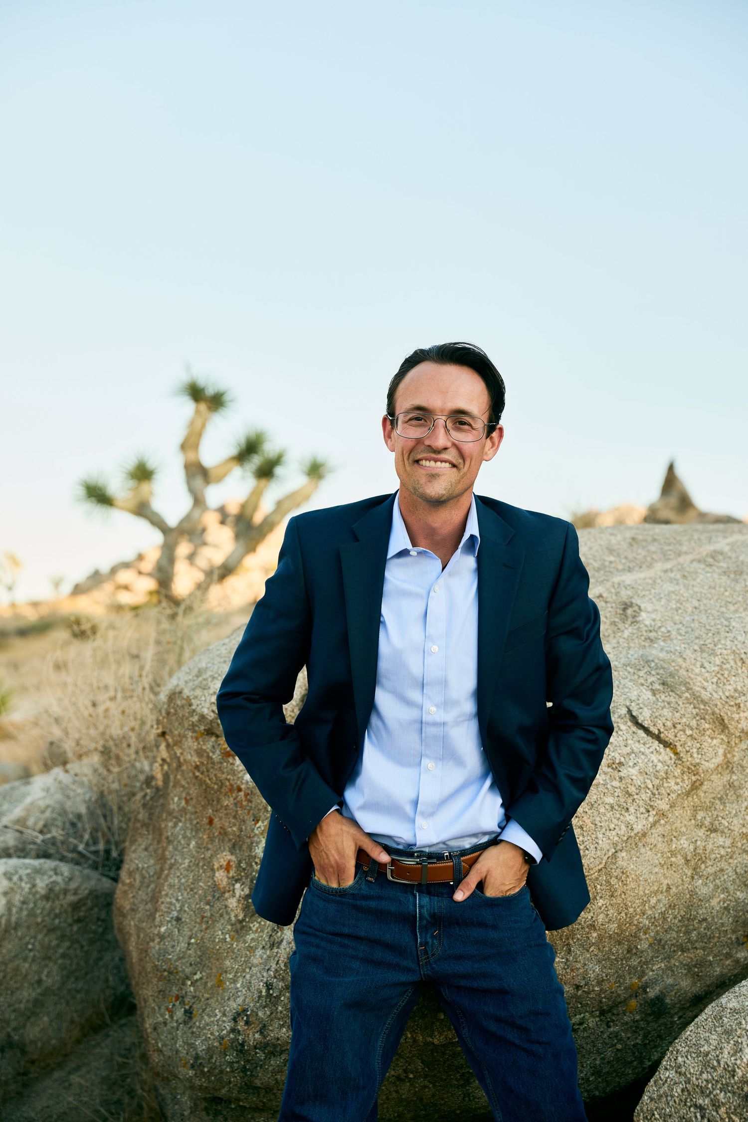 Professional portrait session in desert landscape with natural rock formations and Joshua trees in background.