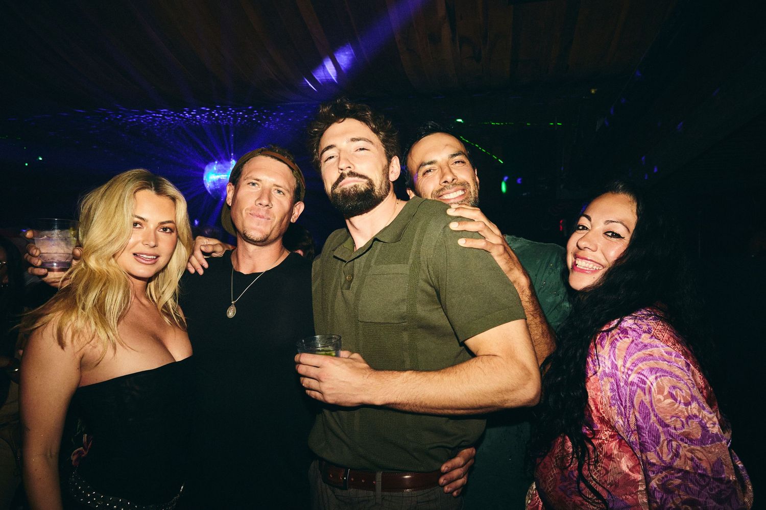 A group of friends having fun at a nightclub with blue lighting and dark atmosphere.