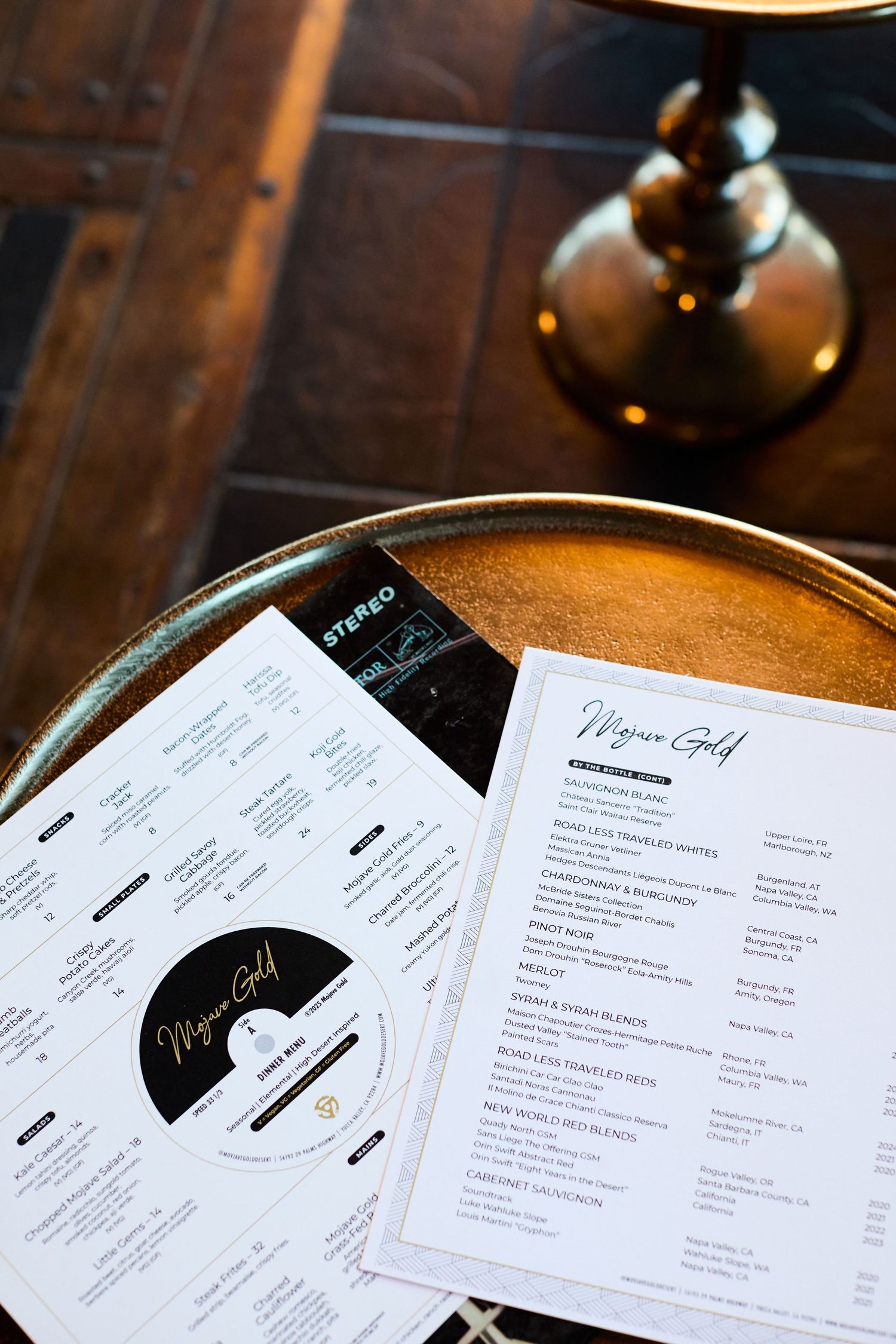 Restaurant menus and drinks list displayed on wooden table with soft lighting.