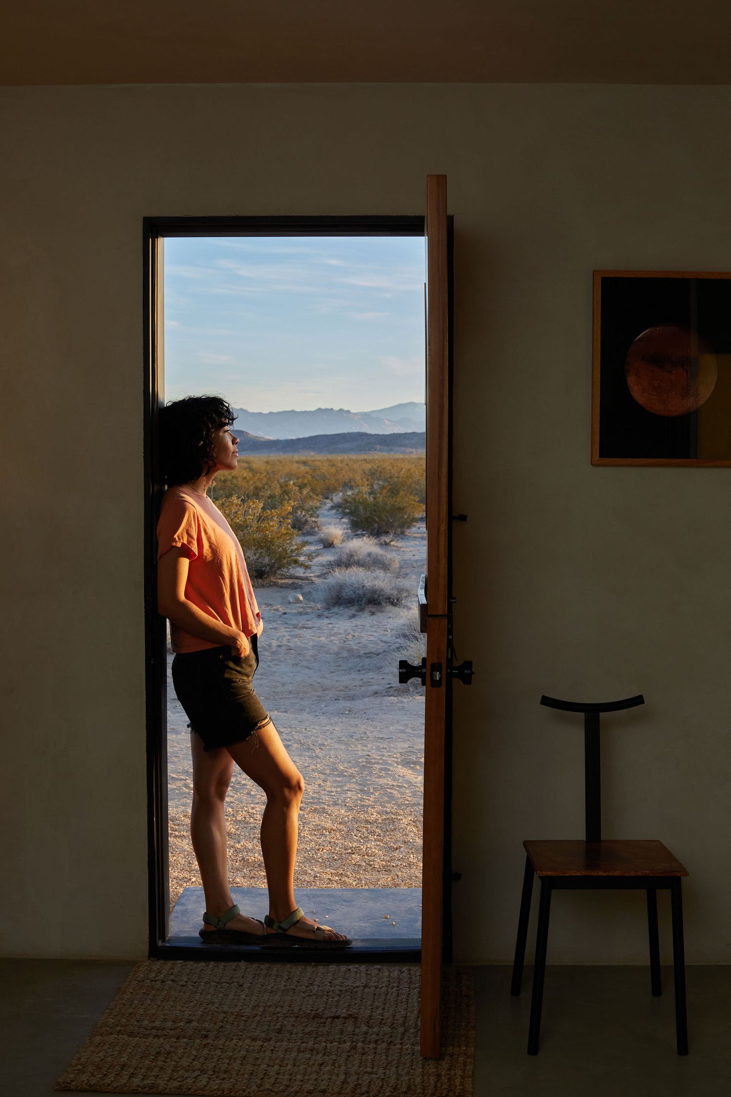 Silhouette standing in doorway overlooking desert landscape.
