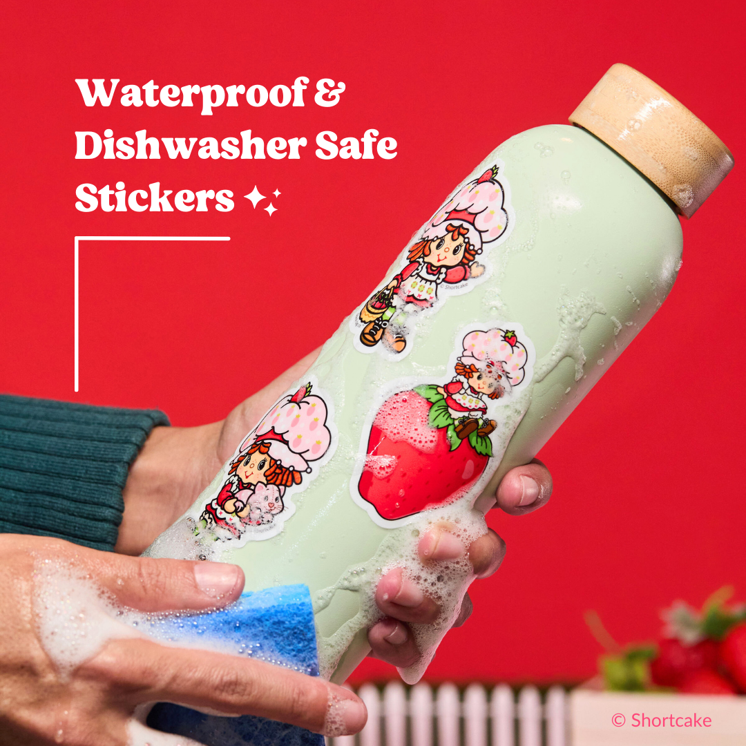 A water bottle decorated with Strawberry Shortcake stickers being shown against a red background.