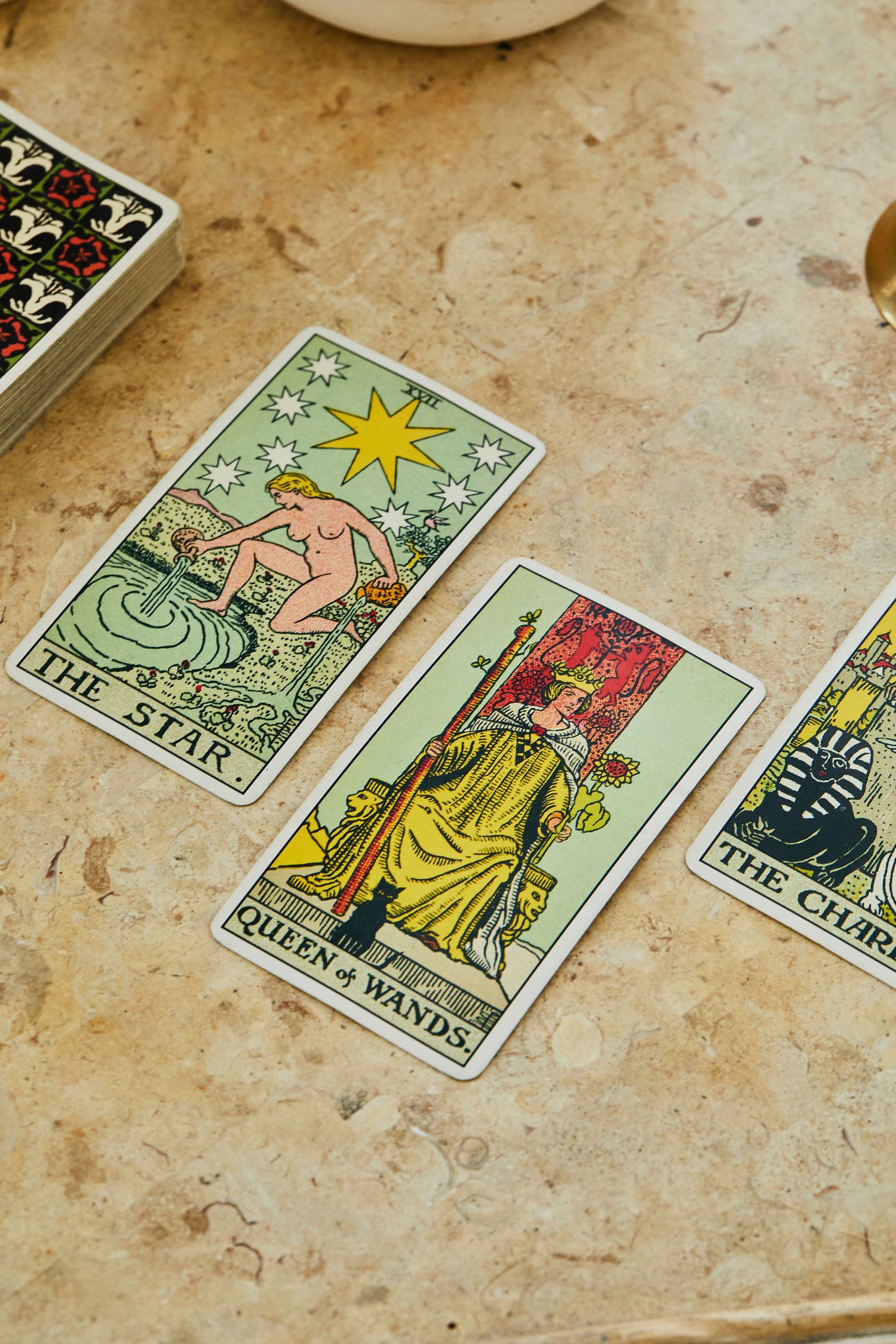 Three tarot cards laid on a marble surface, showing The Star, Queen of Wands, and The Chariot from a classic Rider-Waite deck.