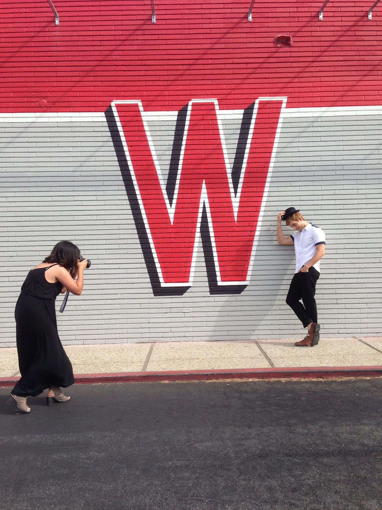 A figure in black moves against a bold red and white wall displaying large text letters in a sequence of motion.
