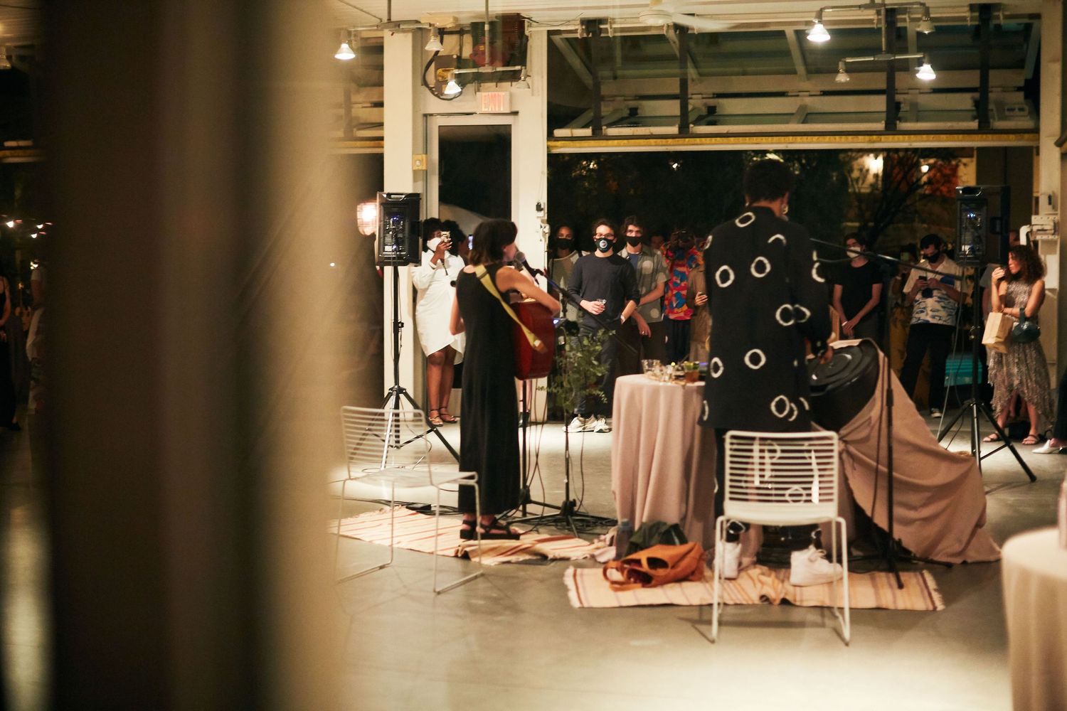 Musicians performing on stage in a dimly lit indoor venue with bubble machines.