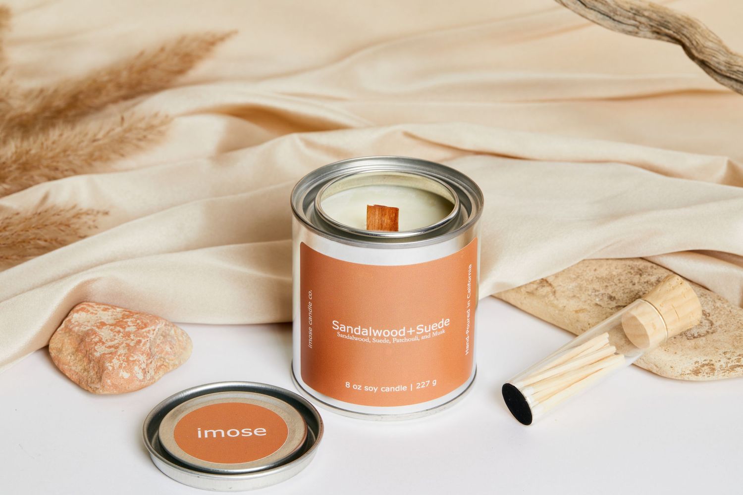Minimalist peach-colored candle in tin container with wooden wick.