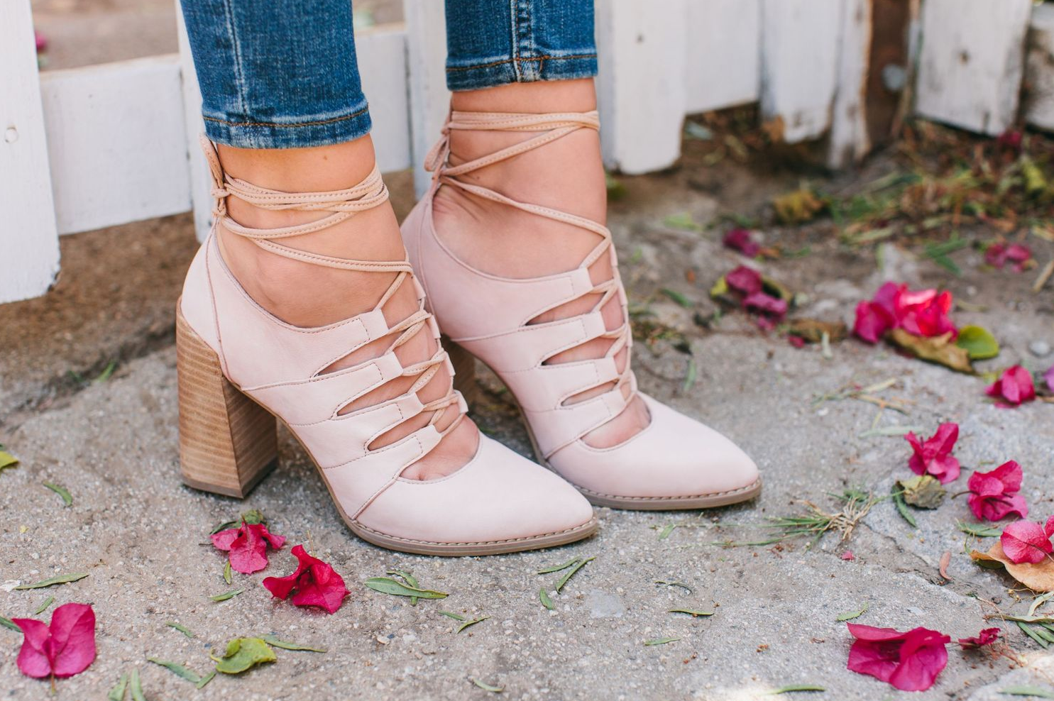Pink lace-up block heel shoes photographed with scattered rose petals.