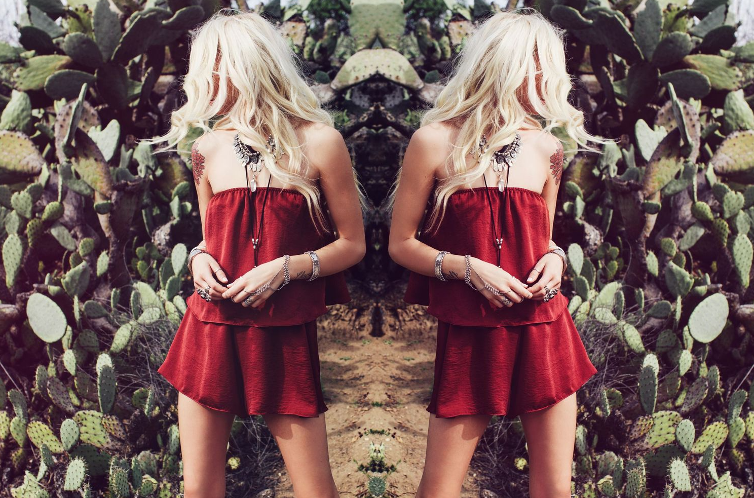 Mirrored image of red summer dress against leafy background in symmetrical composition.