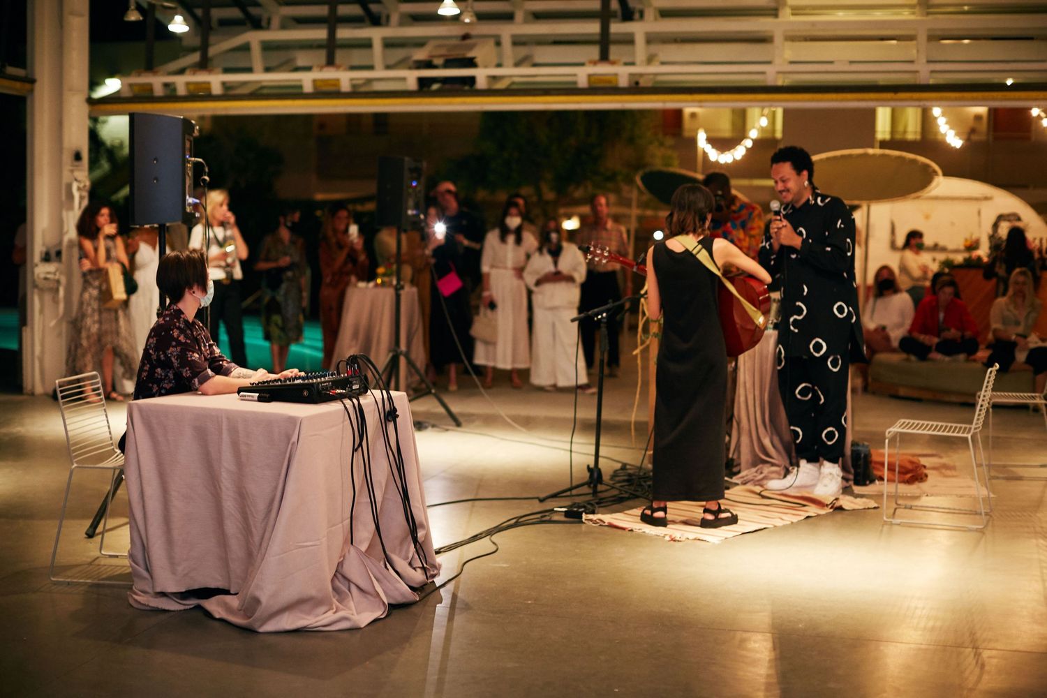 Musicians perform on stage at an event venue with purple lighting and draped tables.
