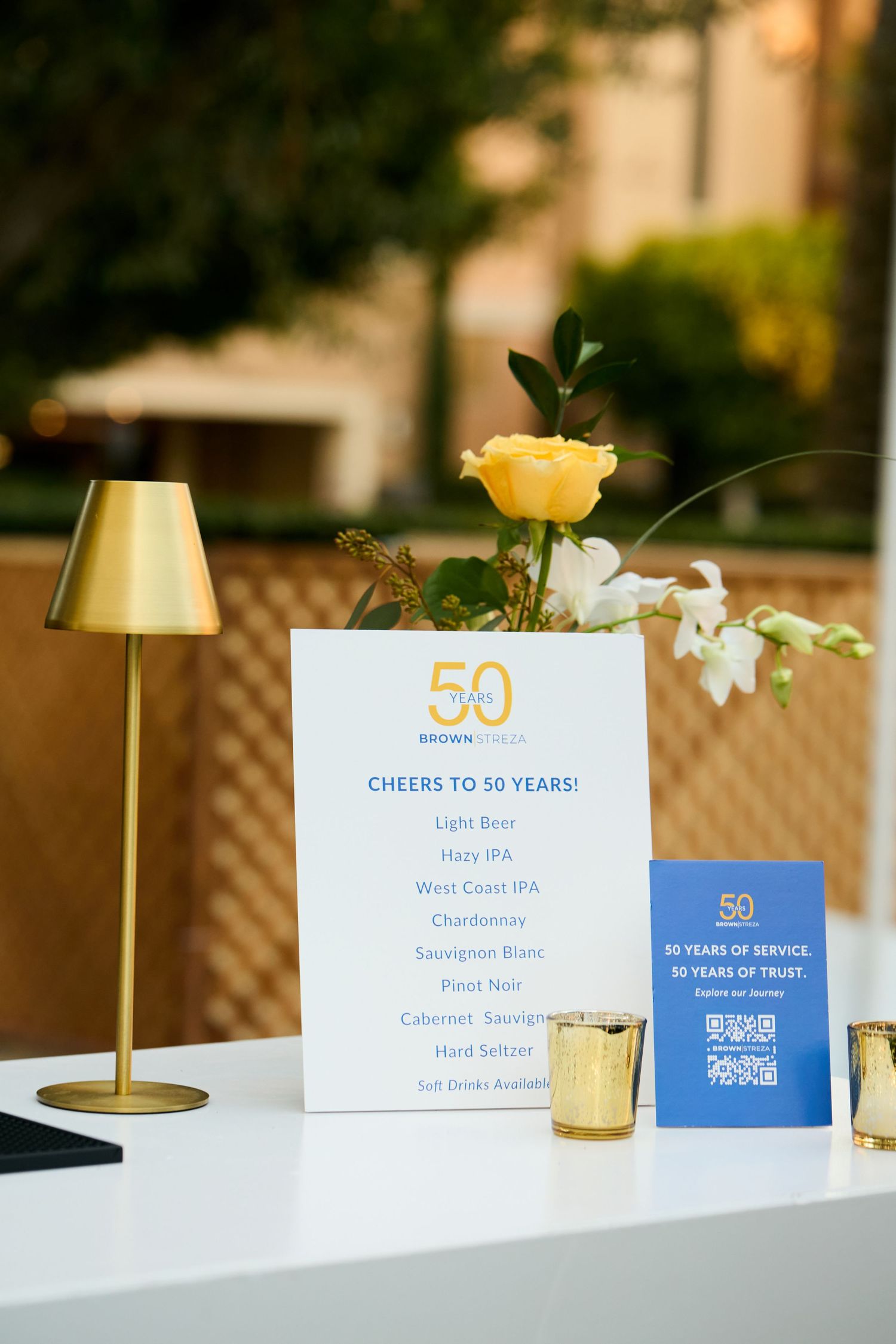 Elegant table setting with blue and white 50th anniversary celebration cards and small floral centerpieces.