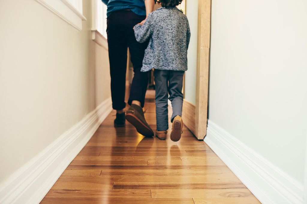 Low angle view of feet walking down hallway with wooden flooring.