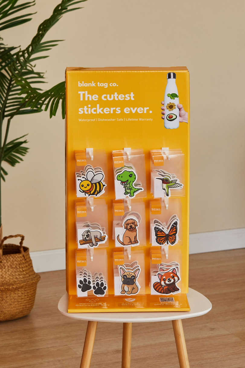 Display of cute animal and food stickers on orange retail stand.