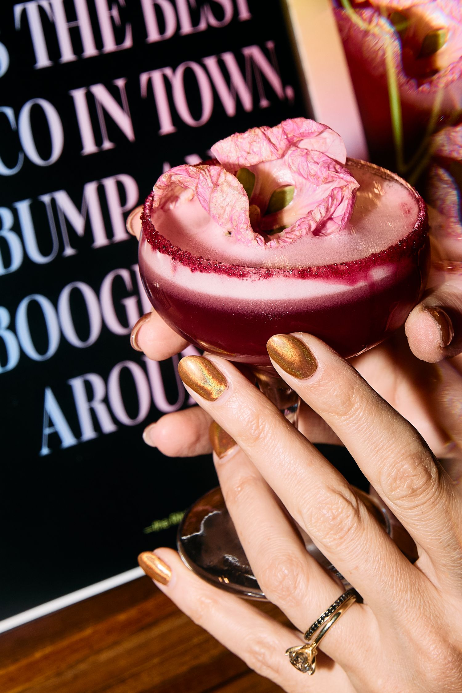 Closeup sequence of hands holding pink lattes or beverages against a dark background with text signage.