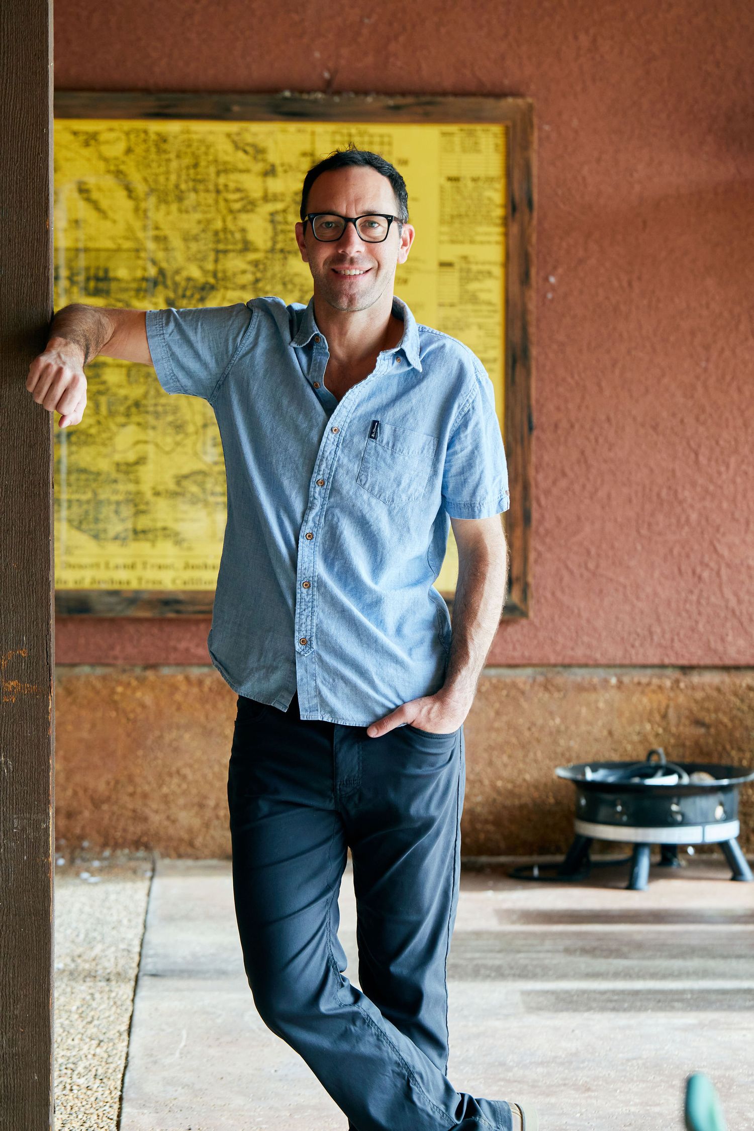 Man in blue shirt leaning against wall with yellow map.