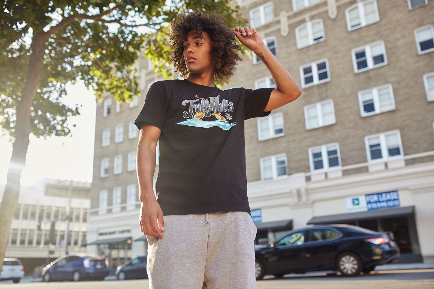 Street style fashion shot of person in graphic t-shirt against urban backdrop.