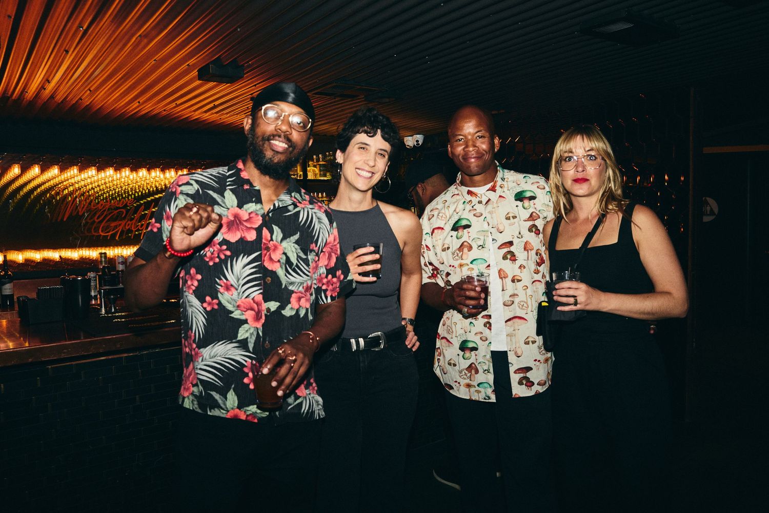 People in floral print outfits dance and socialize at a dimly lit nightclub venue.