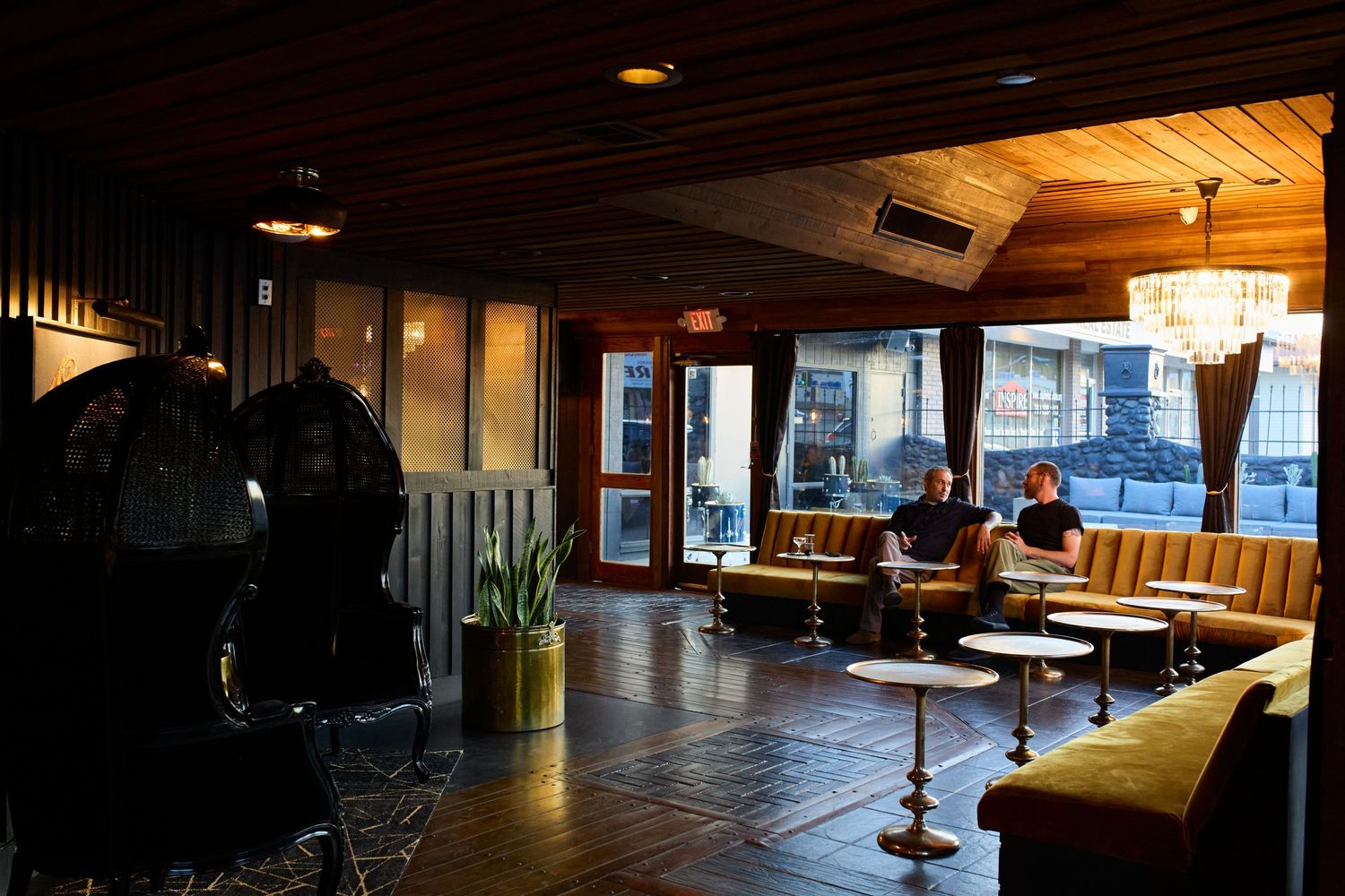 Modern restaurant interior with dark wood tables and ambient lighting creating a warm, cozy atmosphere at nighttime.