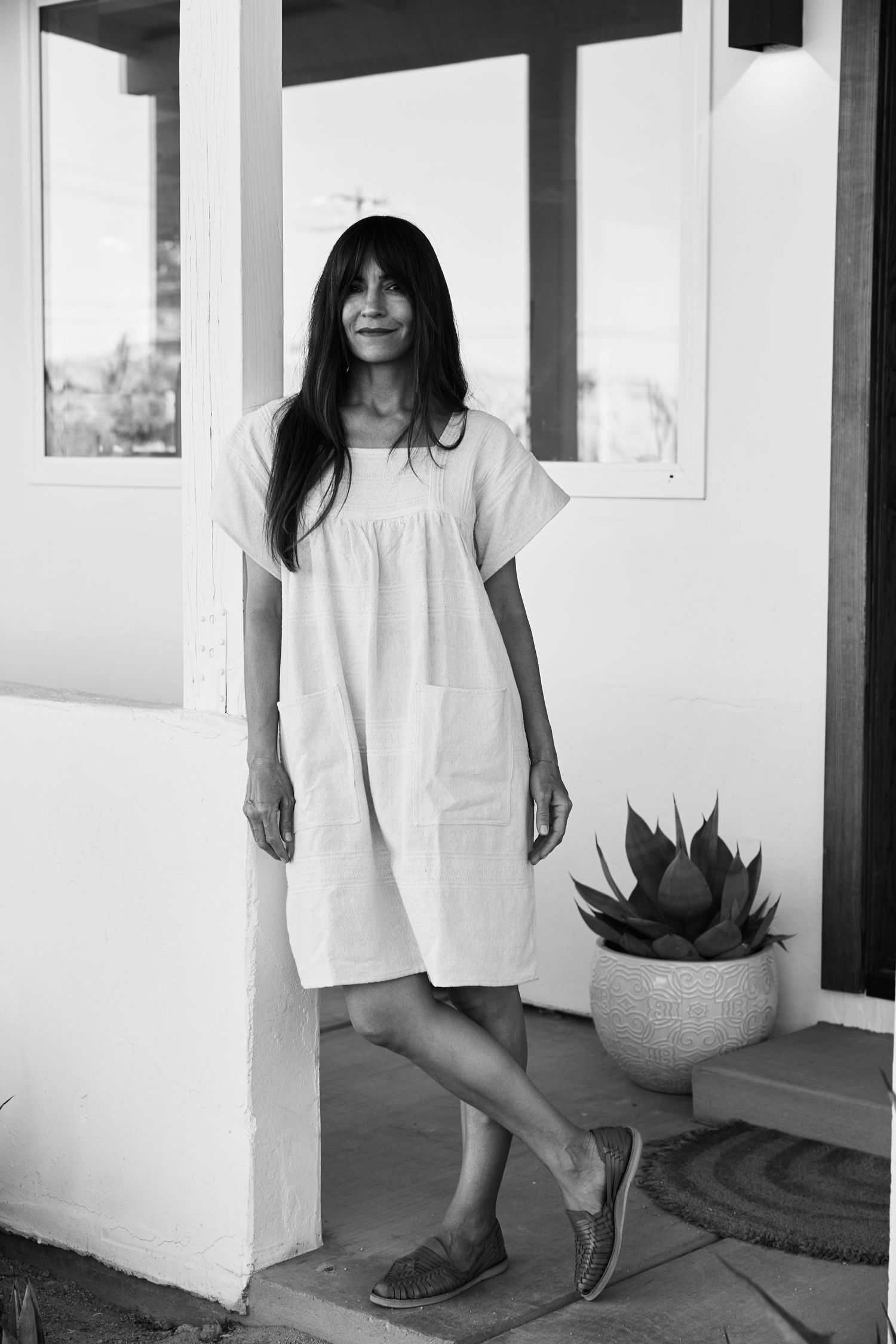 A series of cropped black and white photographs showing parts of a person in white clothing standing against white columns.