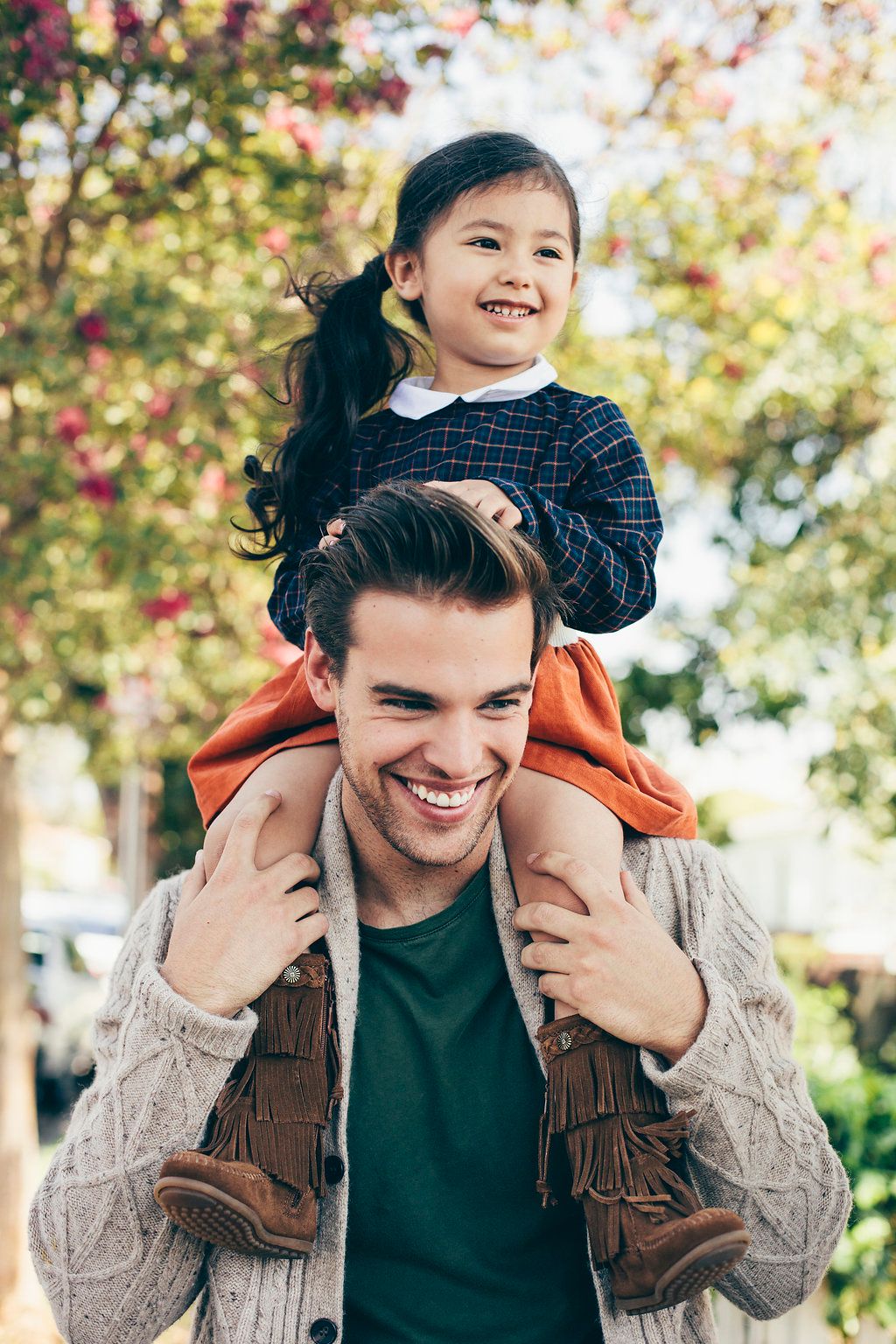 Parent and child share joyful moment outdoors during autumn season.