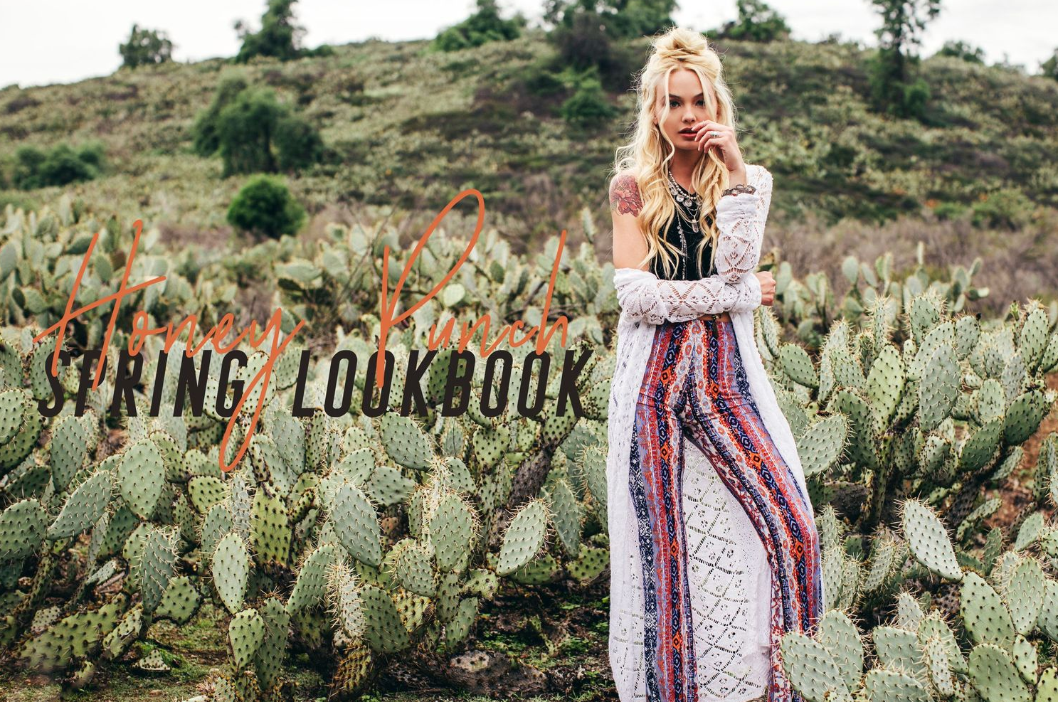 Bohemian fashion shoot in desert landscape with flowing maxi dress surrounded by blooming cactus plants.