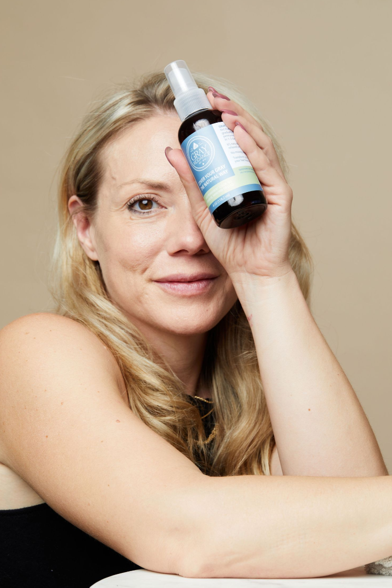 Product photo showing natural hair care spray bottle against neutral background.