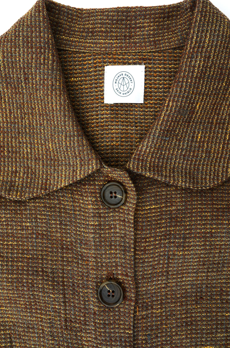 Detailed view of brown tweed coat collar with dark buttons and brand label.