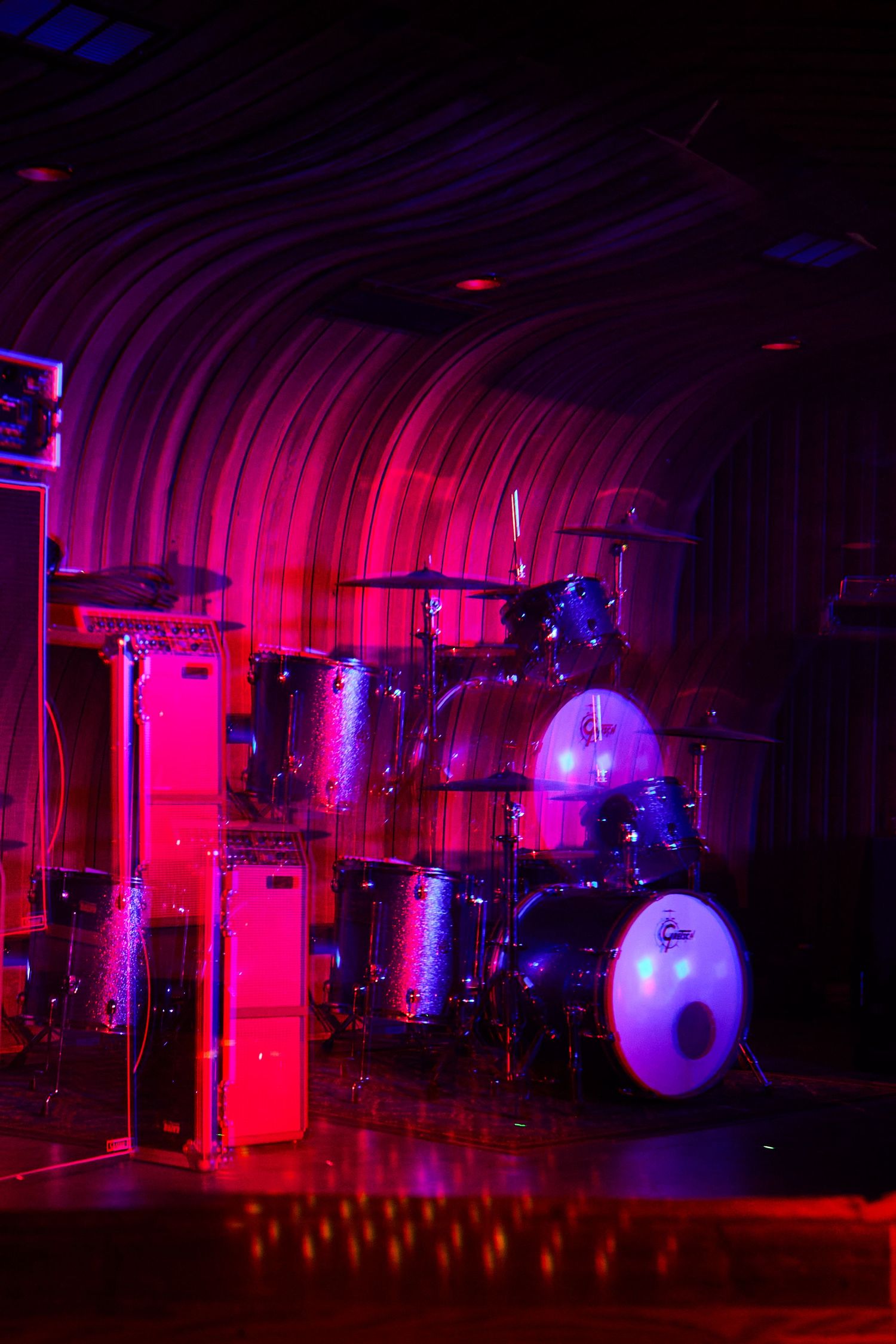 Dark nightclub stage illuminated with dramatic pink and purple lighting effects.