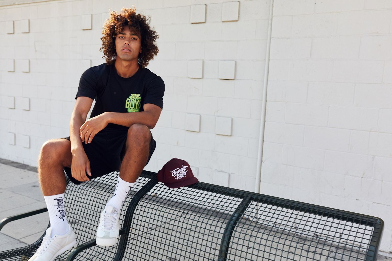 Person in athleisure wear sitting casually on metal bench outdoors.