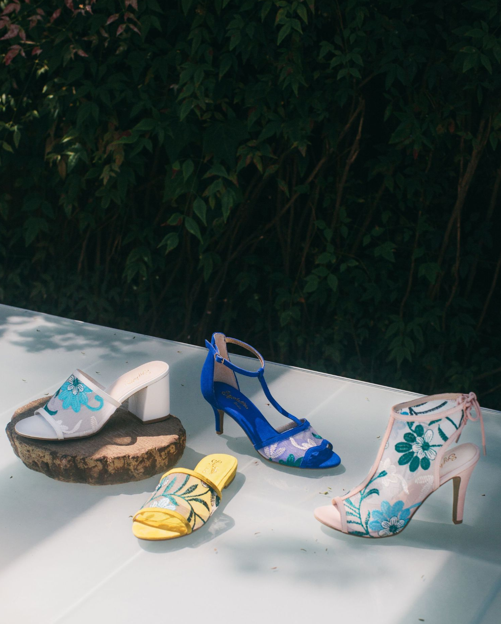 Collection of floral printed summer sandals and heels displayed outdoors.
