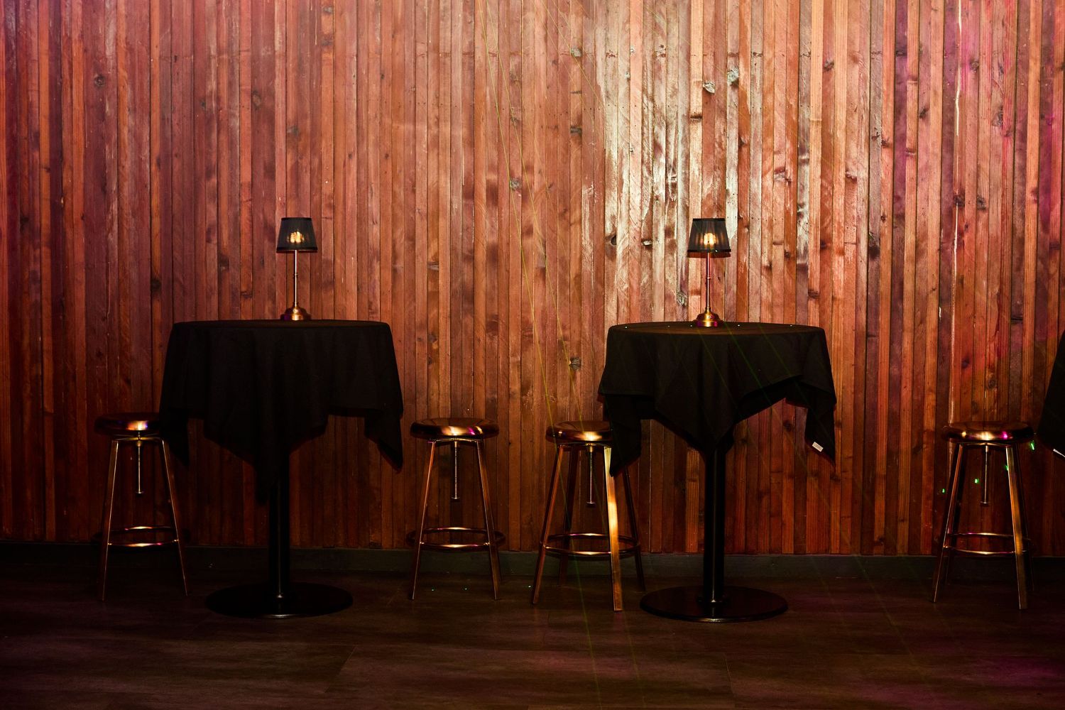 Rustic wooden wall paneling with ambient lighting and dark furnishings.